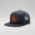 Navy blue cap with brown leather patch on a white background