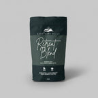 Dark green coffee bag labeled 'Retreat Blend' by Sanctuary Hills on a light gray background