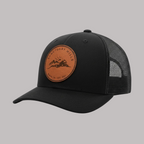 Black trucker cap with a brown leather patch on a white background